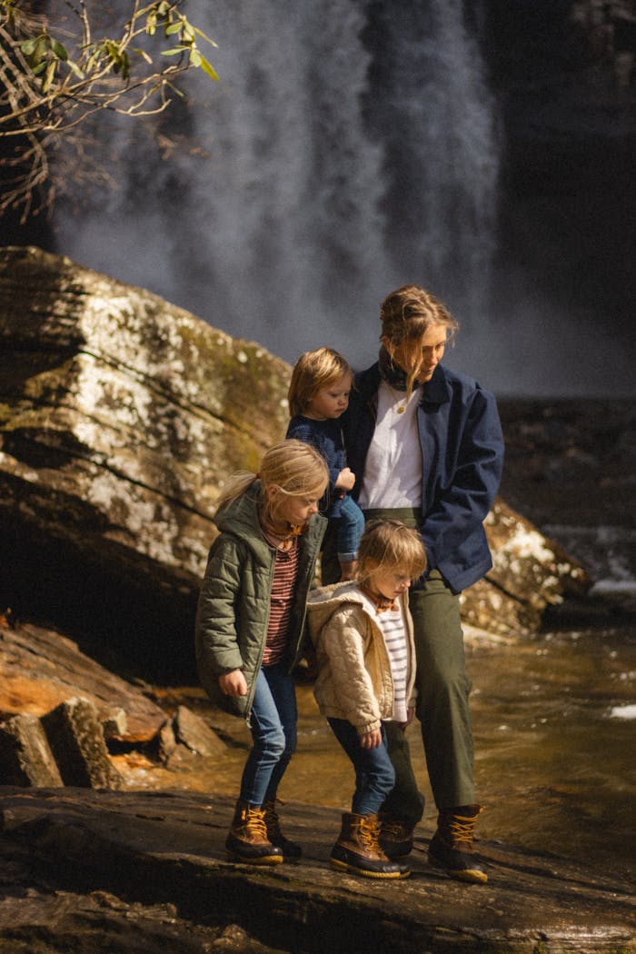 A family enjoys an autumn hike by a stunning waterfall, embracing nature and togetherness.